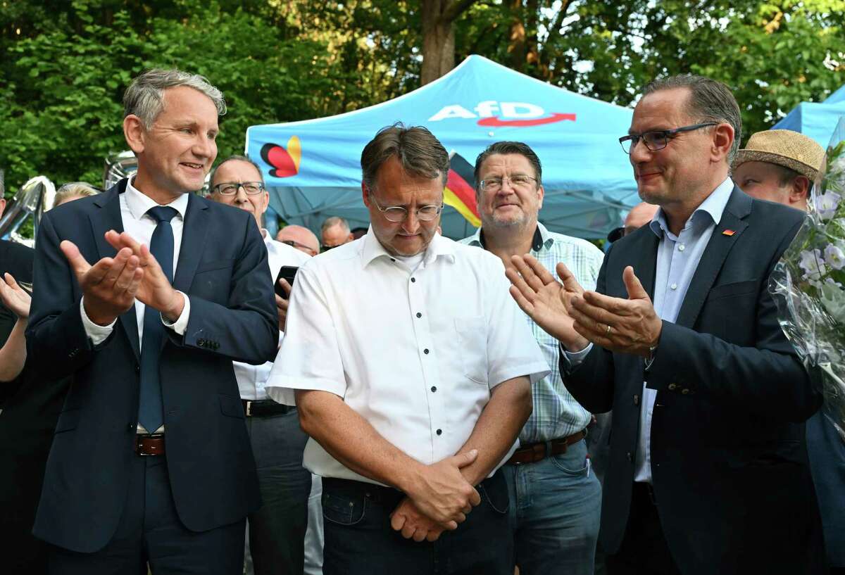 AfD party leader in Thuringia Bjorn Höcke (left) and National party co-leaderTino Chrupalla (right) applaud Robert Sesselmann (center).