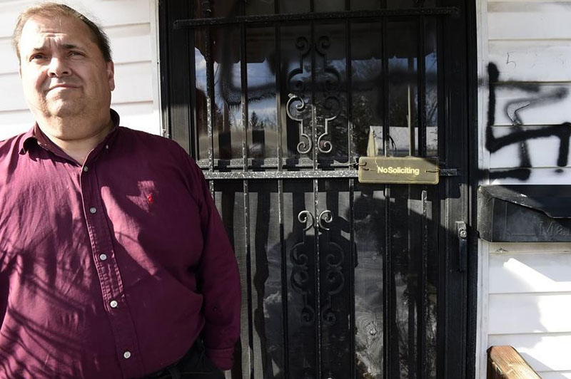 Andrew King stands at the front door of his home in New York state after rerporting that three swastikas were spray-painted by vandals.