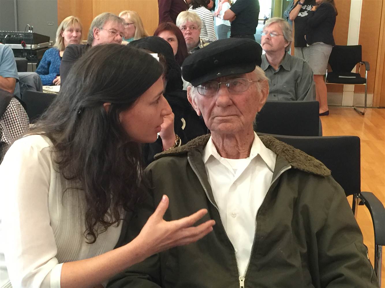 Joshua Kaufman's daughter, who accompanied her father to Germany, speaks with him in the courtroom at the trial of the man he wants to testify against.