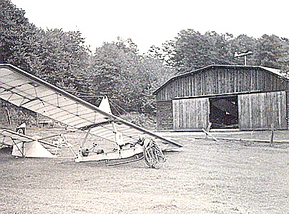 Glider in field near barn.