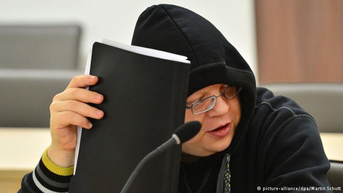 Tino Brandt covers his face as he testifies in the Munich Higher Regional Court
