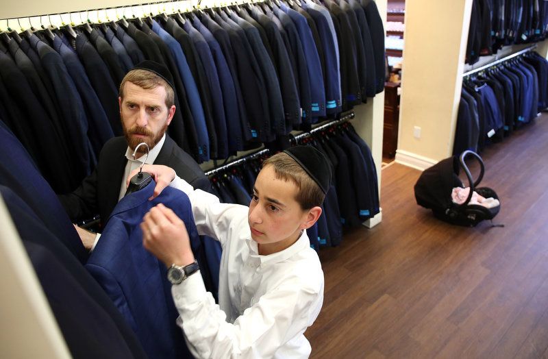 Yehuda Braun, 14, shops for a new suit at "His Place" men's and boy's clothing store in Lakewood, owned by Gedalia Tomor.