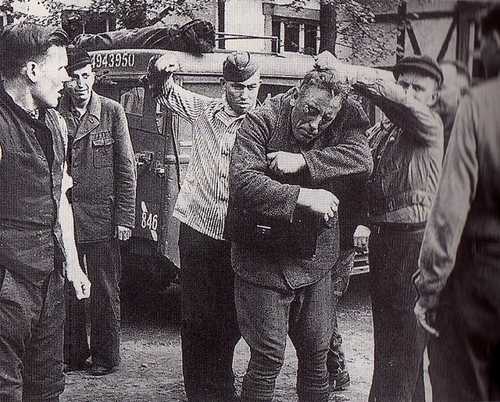 Liberated inmates of a concentration camp getting back at a Kapo.